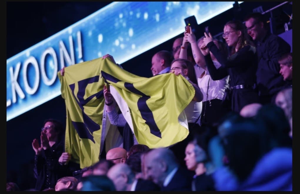 In the crowd, Aisti Sport members celebrate and wave a flumino-coloured banner reading 'Aisti'.