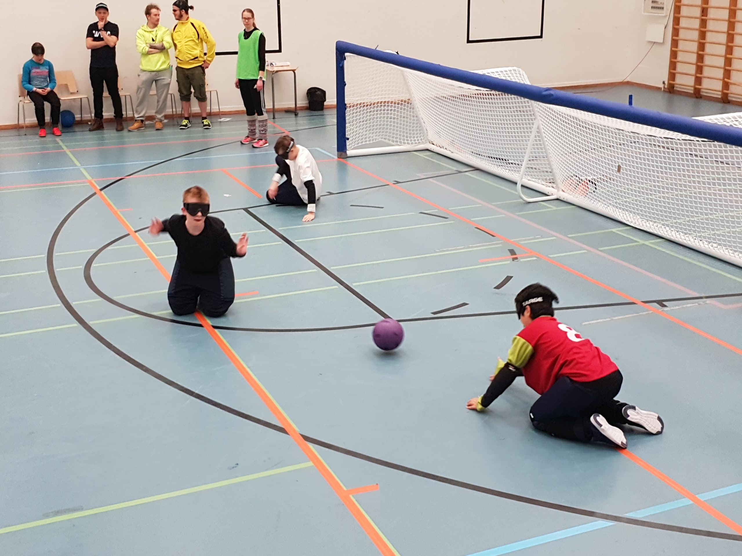 Kuva maalipallokentältä jossa lapsisentteri syöttää pallon lapselle seiskalaidassa. Toisessa laidassa näkyy muutaman vuoden vanhempi pelaaja kylkiasennossa