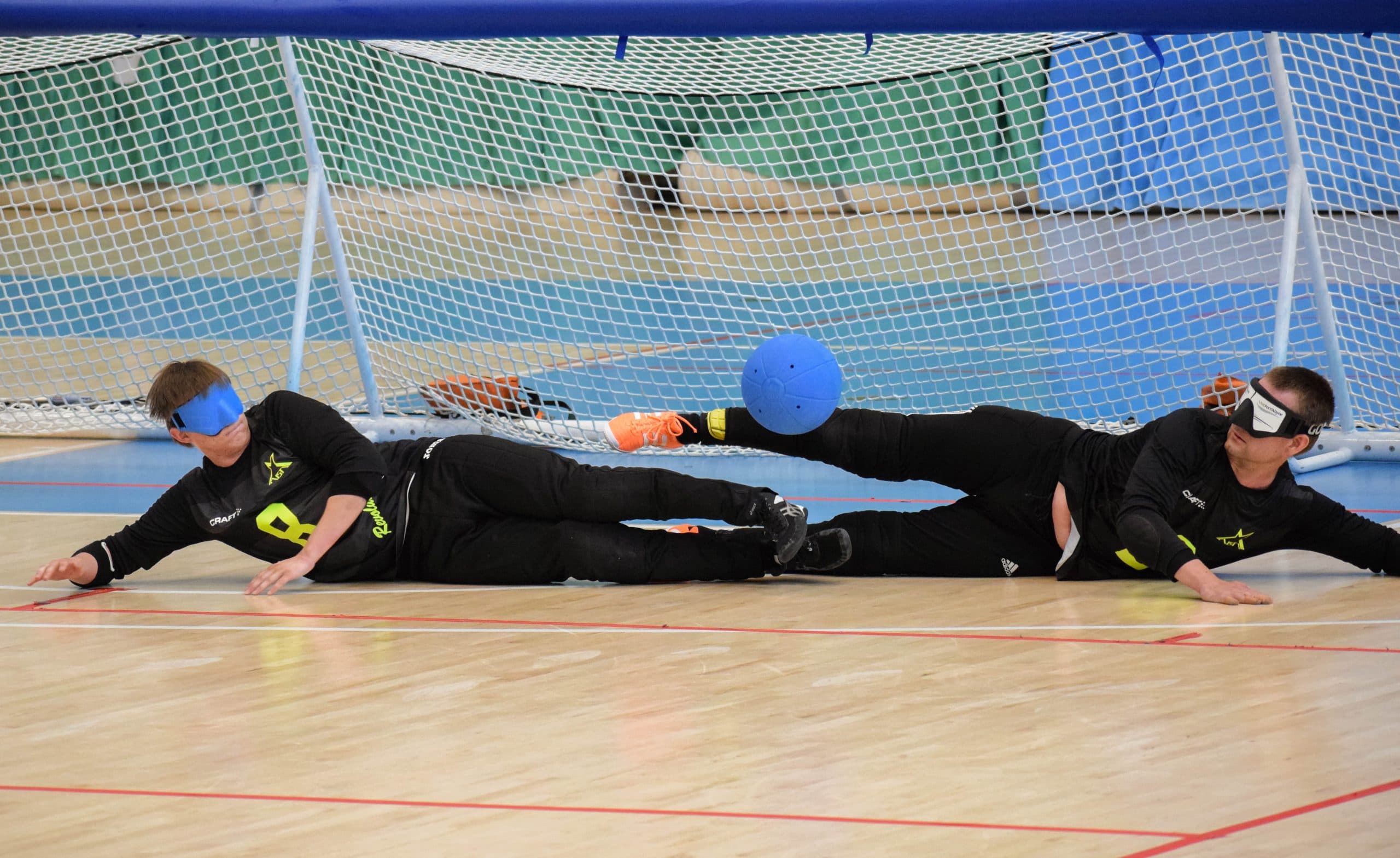 An action shot where young men in Aisti Revolution jerseys — the centre and the wing on the right — slide to block a throw that has come between them.
