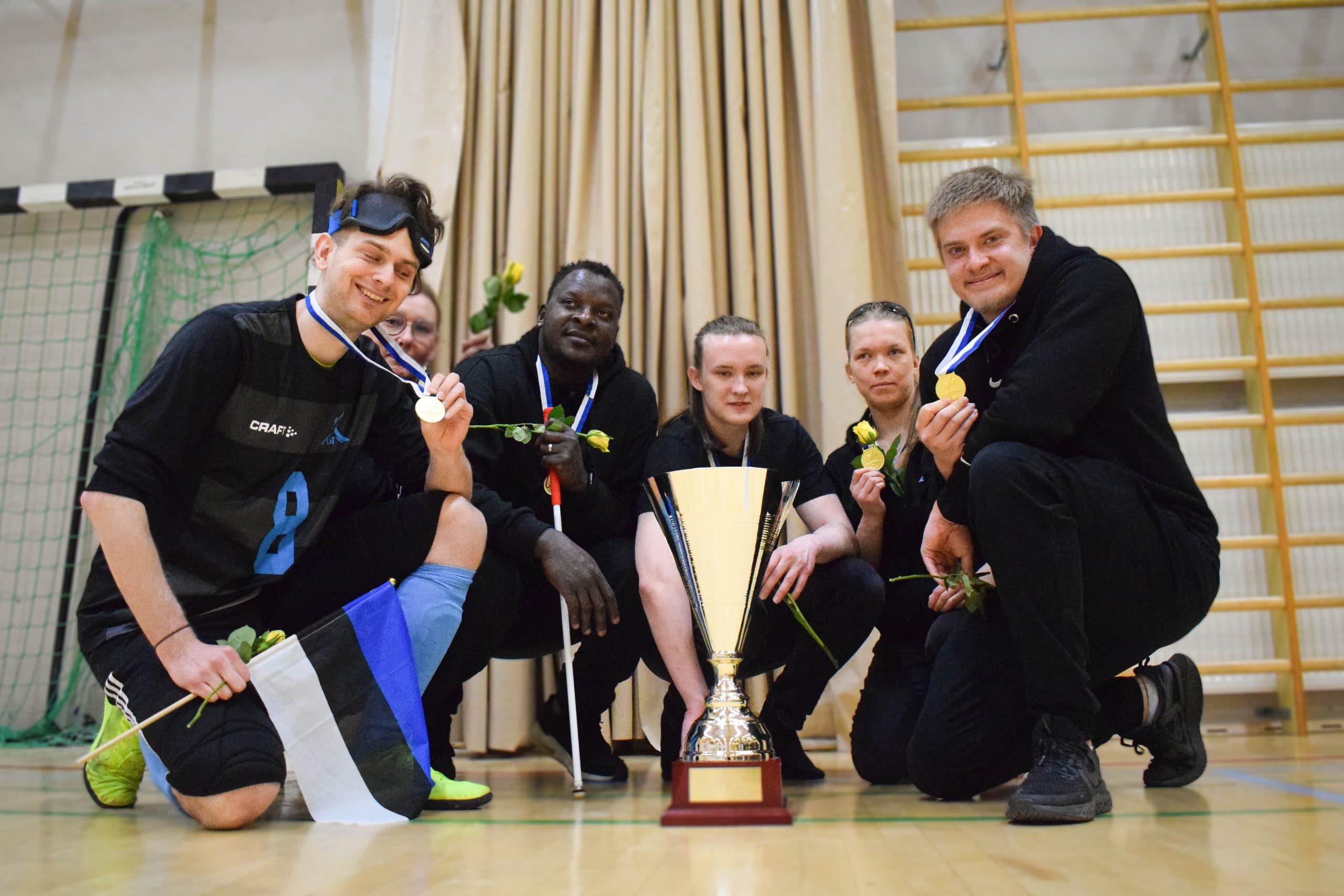 A championship photo of the team, the whole team kneeling around the winners' trophy. Order from left to right: Krister, Miia, Bruno, Leo, Raisa and Aleksi.