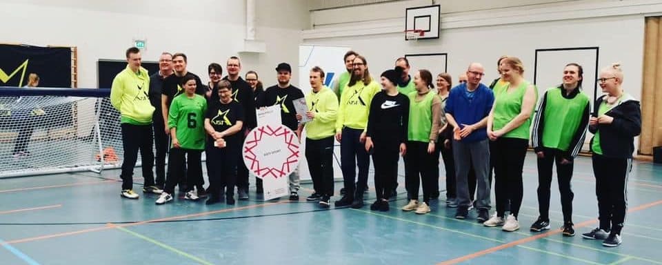 Kuvassa yli 20 Aisti Sportin jäsentä ja vapaaehtoista toimitsijaa tuulettamassa tähtiseura-meriittiä.