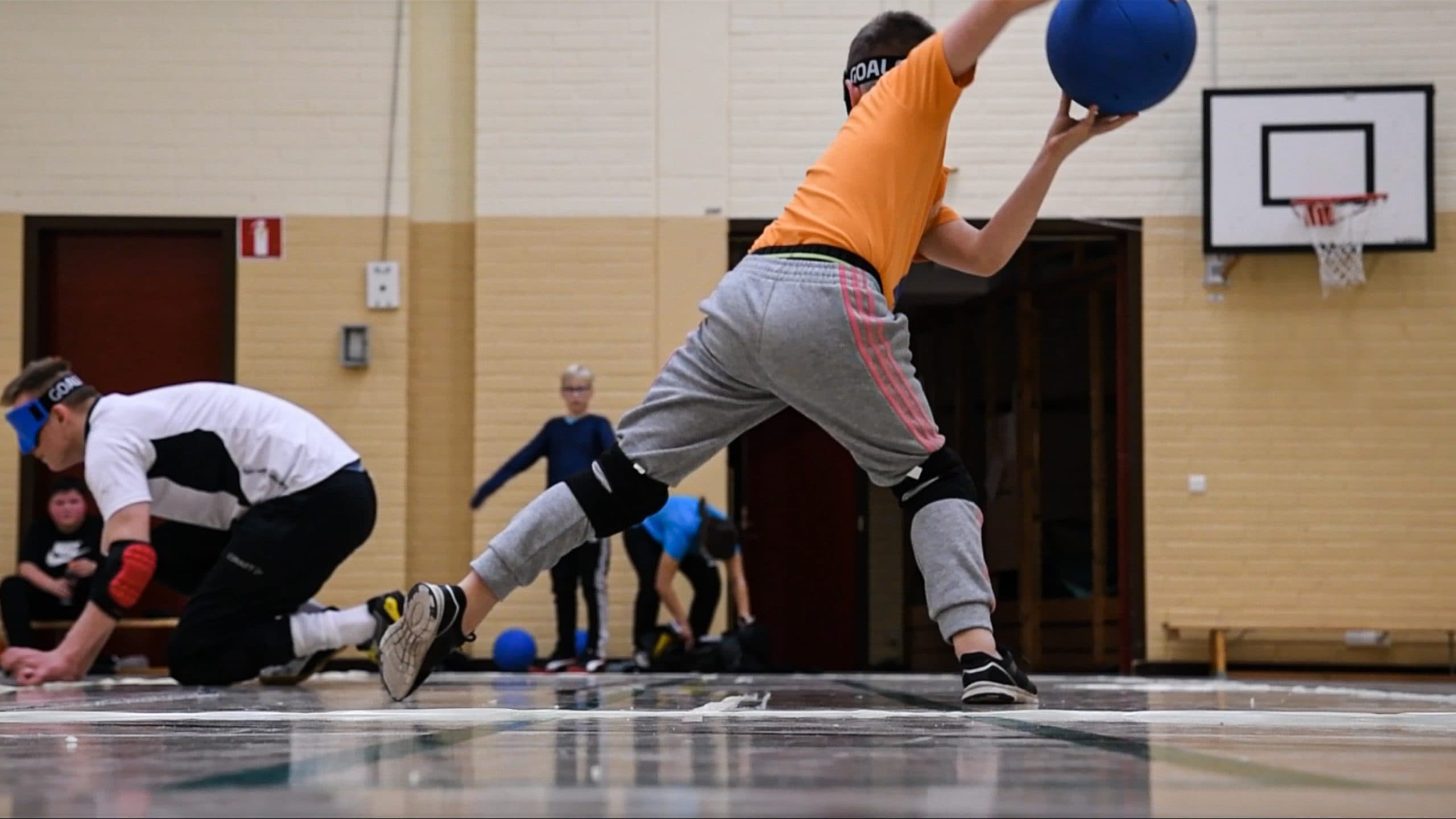 A boy throwing the ball, hands still pointing back and up. The photo is taken from behind.