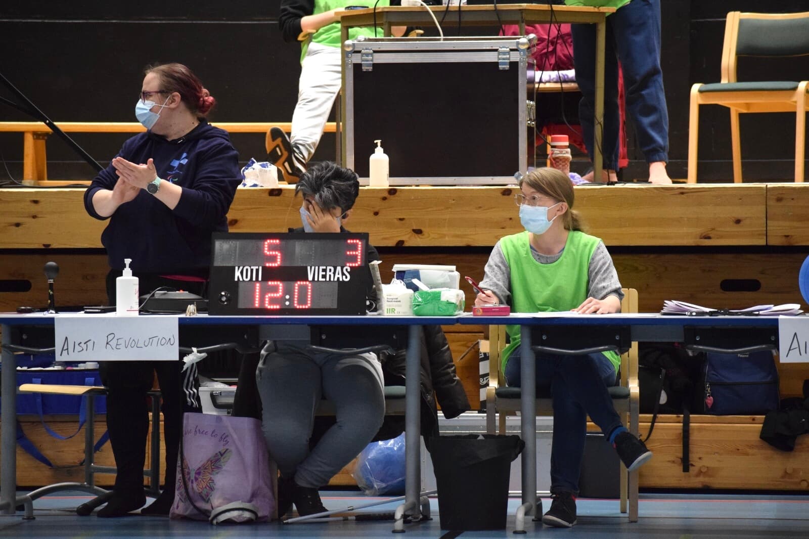 Three women working at the officials' table. In front, the game clock and the score 5–3 are visible.